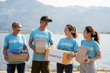 Team of volunteers smiling and holding donations boxes, donations bag in outdoor. social worker making notes charity