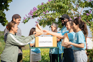 Team of volunteers smiling and holding donations boxes in outdoor. Volunteers putting food in donation boxes, social worker making notes charity