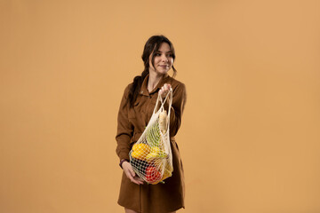 Zero waste concept. Young beautifull brunette woman holding reusable mesh shopping bags with...