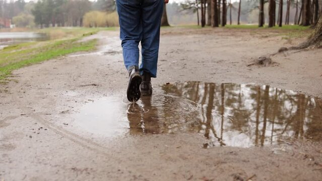 Female feet walking in park forest on rainy day. Travel concept, close-up woman legs walking in hiking shoes by wet ground. Walk journey concept. 