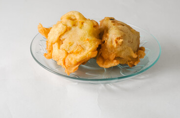 two pieces of fried tofu stuffed with vegetables served on a small plate isolated on a white background