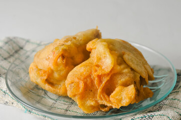 two pieces of fried tofu stuffed with vegetables served on a small plate with a napkin isolated on a white background