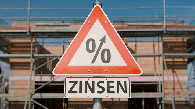 Steigende Bauzinsen - Schild vor Eigenheim Neubau