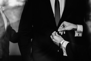 Closeup of groomsmen helping groom to get ready for the wedding ceremony.