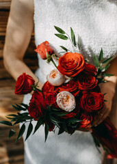 Closeup of a bride holding a big bridal bouquet made of red roses.