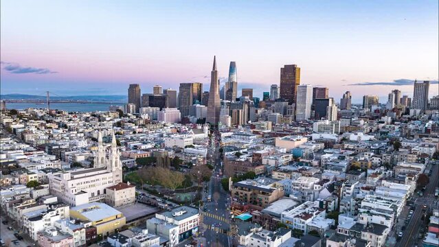 Fly above Columbus Ave and heading to Transamerica Pyramid and other skyscrapers in financial district. Hyperlapse footage of downtown at twilight. San Francisco, California, USA
