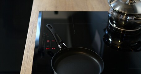Turn on black induction or electrical cooktop surface with frying pan. Comfortable kitchen equipped...