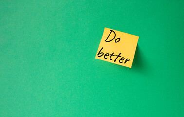 Do better symbol. Orange steaky note with concept words do better. Beautiful green background. Business and Do better concept. Copy space.