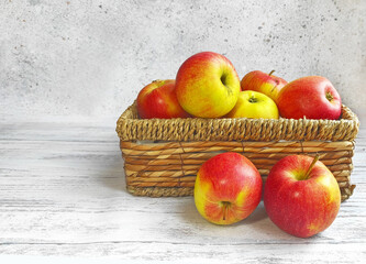 Wicker basket box with red juicy apples close up on a wooden white table. Fruit harvest. healthy eating concept.  space for text