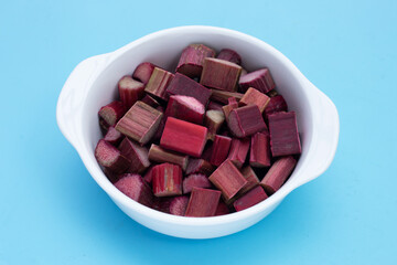 Fresh rhubarb in bowl on blue background.