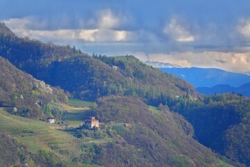 Blick über eine Landschaft in Südtirol bei Meran mit einer kleinen Burg umrahmt von Wäldern