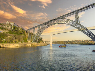 Douro river with traditional sailing wine boat cruise, view of Maria Pia and Sao Joao bridges, typical architecture of cascade housing in sunhine. Rabelo boat in douro river, Porto, Portugal