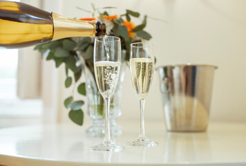 Closeup Of Sparkling Wine Pouring In Glasses On Table Indoors - obrazy, fototapety, plakaty