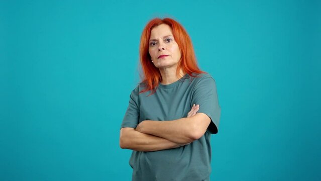 Serious mature redheaded woman looking at camera with arms crossed