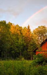 Rain clouds and rainbow over old wooden barn in the countryside