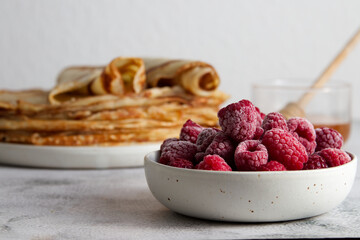 Stack of fresh crepes with honey and raspberries on the table copy space