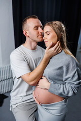 Naklejka premium Happy and attractive pregnant woman and her husband are hugging and happy in anticipation of childbirth. Cheerful family pregnant couple