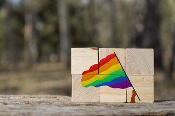 Person holding a lgbt community flag over some wooden cubes