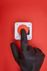 The hand in black vinyl glove, which pushes the emergency button at the red background at the top view - obrazy, fototapety, plakaty