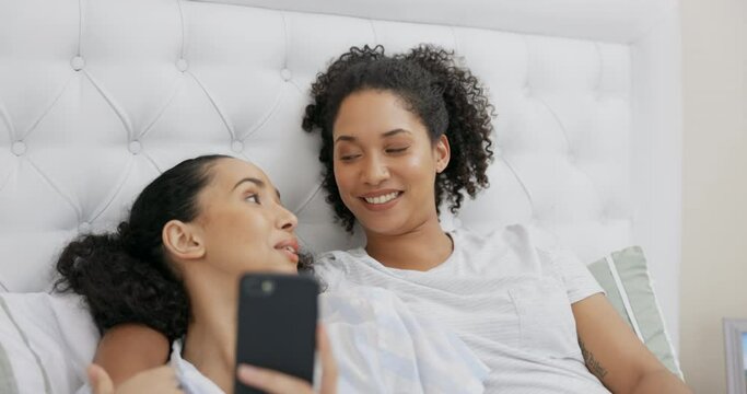 Phone, bed and happy couple of friends relax with social media post, funny meme or reading internet blog at home. Young gen z woman or lesbian people talking of lgbtq love, care and chat in bedroom