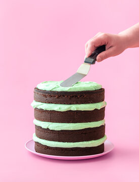Making chocolate layer cake with mint flavor cream, isolated on a pink background