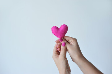 mãos de mulher com unhas rosa segurando coração rosa, conceito de amor e cuidados da mulher 