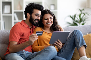 Online Shopping. Indian Couple Using Digital Tablet And Credit Card At Home