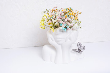 Mental health concept. Creative plaster vase head-shape with colorful flowers and butterfly