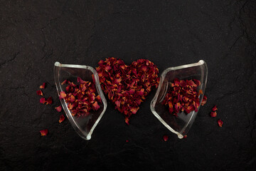 Broken glassware and heart-shaped rose petals on dark background. Abstract Concept of quarrel,...