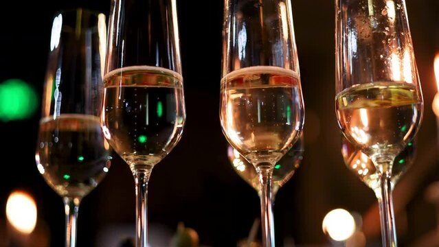 many glasses with wine or champagne in a dark room restaurant,fourchette table. barman open with corkscrew the bottle.evenimente poor light conditions 4k video