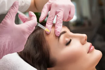 Photo sur Plexiglas Salon de beauté Cosmetologist does injections for lips augmentation and anti wrinkle injections of a beautiful woman. Women's cosmetology in the beauty salon.