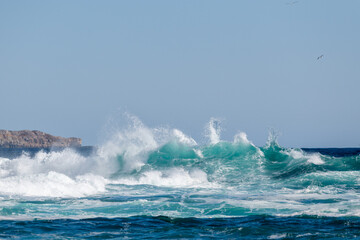 An angry turquoise green color massive rip curl of a wave as it barrels rolls along the ocean. The...