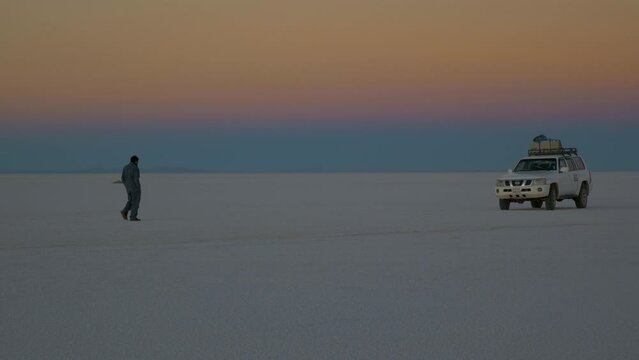 A driver walks to his car at dusk in the Uyuni Desert, Bolivia