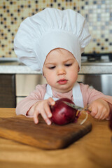 Little girl Cooking in the kitchen wearing an apron and a Chef's hat.