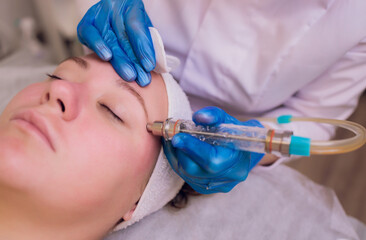 Woman cleaning skin pores using vacuum blackhead remover, cosmetic procedure.