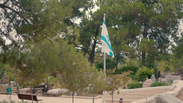 A Jewish cemetery with an Israeli flag waving in the wind.