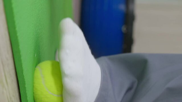 Man doing a foot massage with a special orthopedic ball. Prevention flat feet correction exercise. close up