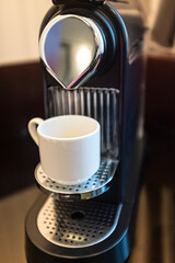 White espresso coffee cup on a domestic capsule black coffee machine
