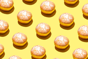 Fresh homemade donuts, creative food pattern, bright yellow background. 