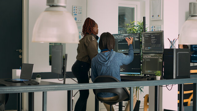 Diverse team of database admins analyzing source code and comparing data script in busy agency room. Cloud programers working on system interface algorithm in development office.