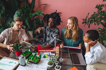 Diverse group of international students working on the urban project of modern city with renewable energy source, green areas. Concept of ecology, environment protection, waste recycling, technology