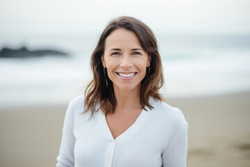 Serenely smiling brunette woman in white attire on beach with blurred sea background. Generative AI
