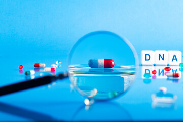 DNA pill on the background of a laboratory table with medicines and preparations. View through a...