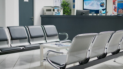 Professional waiting room with chairs in clinic hallway, reception counter used to solve patients registration before medical appointment. Empty reception counter desk in health center.