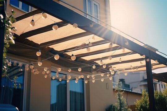 Canvas awning with metal frame and luminous garland of light bulbs against blue sunny sky. modern shading for house, created with Generative AI