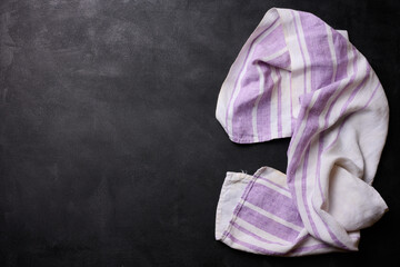 Folded linen linen kitchen towel on a black background, top view