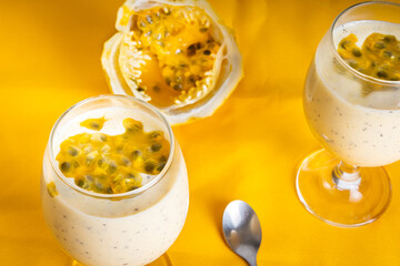 Passion fruit mousse in a glass bowl, with passion fruit in the background, on a Yellow background.