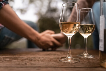 Romantic couple holding hands enjoying glass of wine together outdoors 