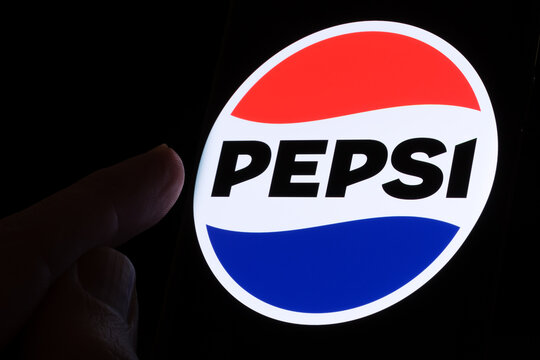 PEPSI new logo introduced in 2023 seen on the screen glowing in the dark and finger is pointing at it. Stafford, United Kingdom, April 3, 2023