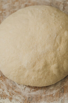 shaping sourdough bread dough into round, boule on floured board